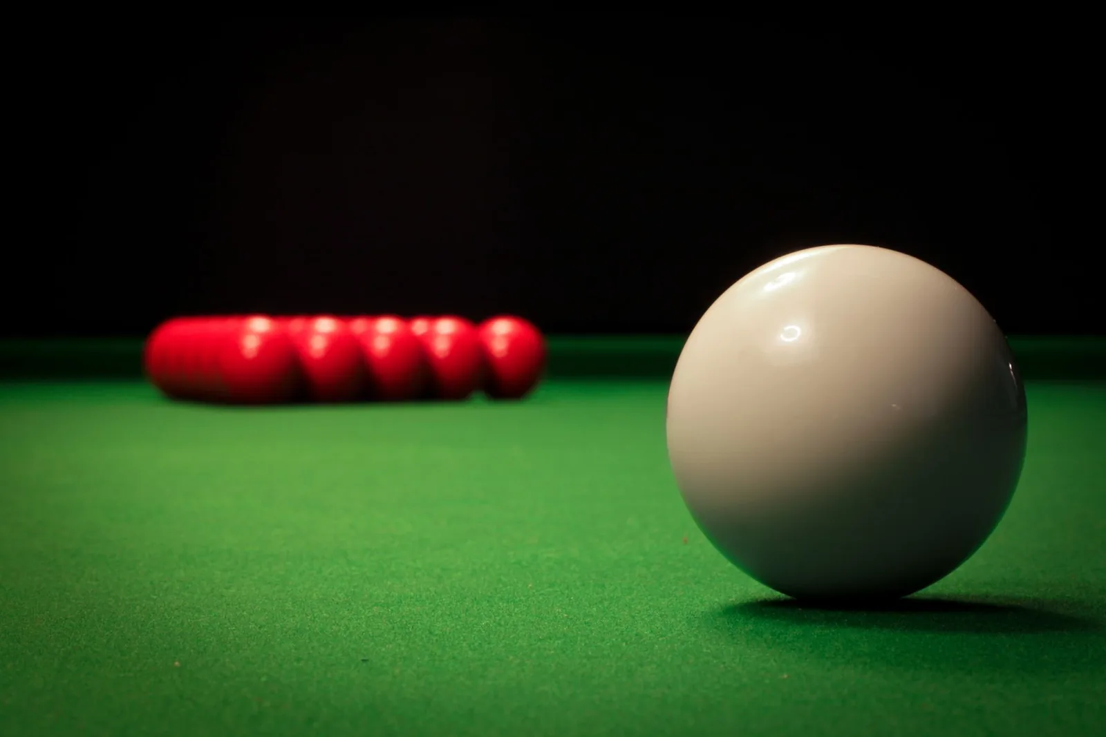 Snookerpöydän vihreä kangas, valkoinen pallo ja punaiset pallot