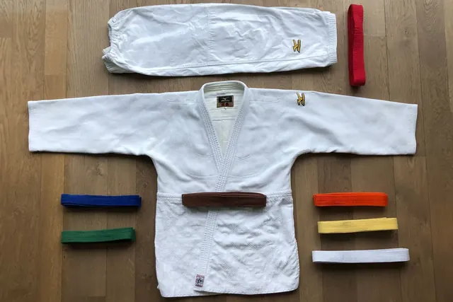 Judopuku ja eriväriset vyöt levitettynä parkettilattialle