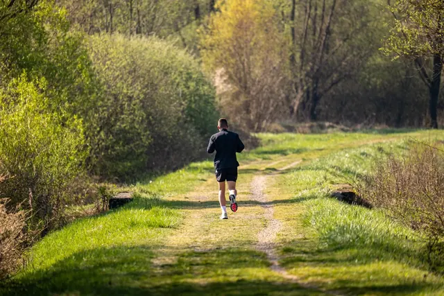 Juoksija nurmipolulla vihreän niityn läpi