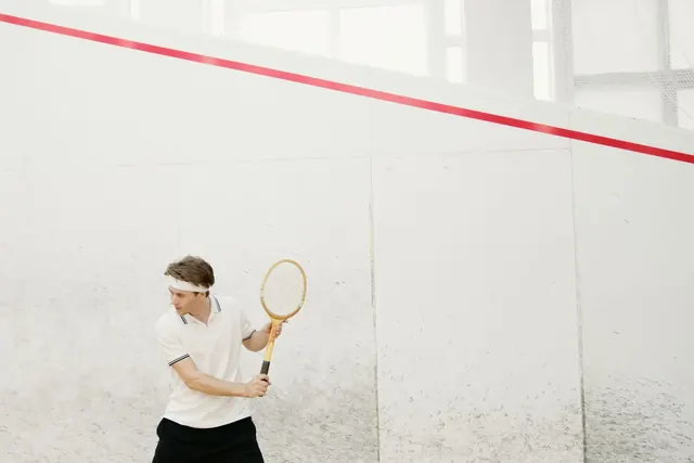 Pelaaja valmistautuu lyömään mailalla squash-kentällä