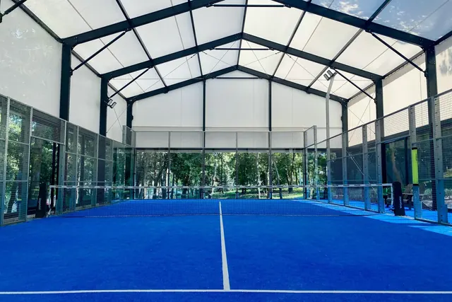 Padelkenttä sinisellä alustalla katetussa hallissa