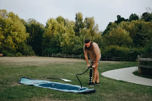 Mies pumppaa SUP-lautaa käsipumpulla puistossa