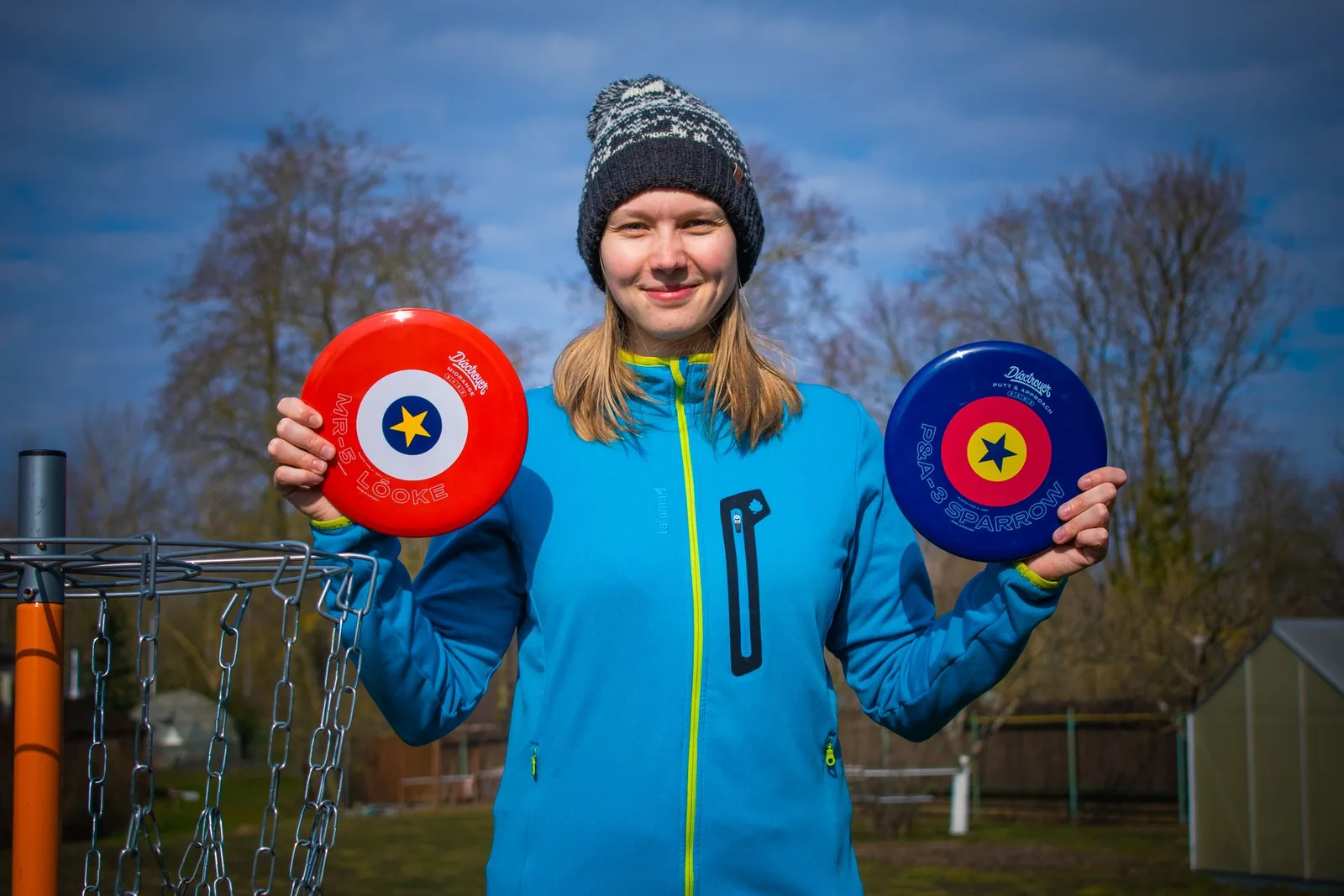 Hymyilevä pelaaja pitää käsissään kahta frisbeegolfkiekkoa